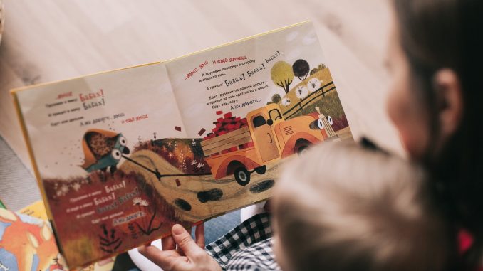 woman reading book to toddler